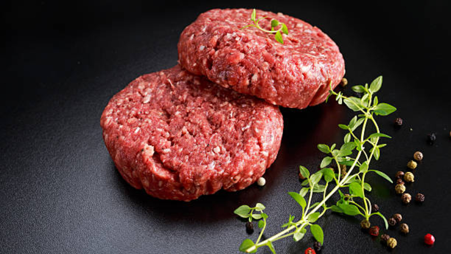 Home HandMade Raw Minced Beef steak burgers on black board.